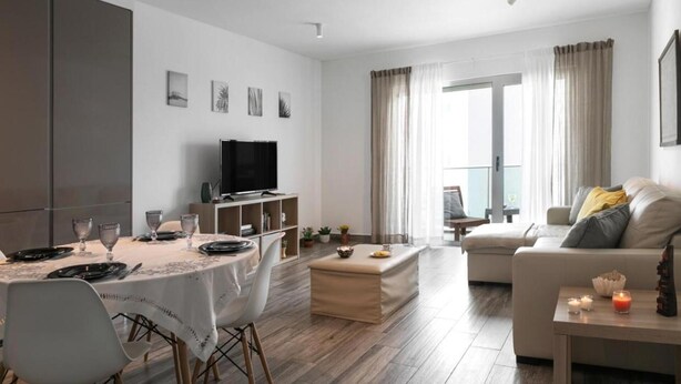Un salon moderne comprenant un coin repas, un téléviseur à écran plat et un canapé agrémenté de coussins.
