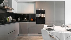 Une cuisine moderne dotée d’appareils électroménagers en acier inoxydable, d’un plan de travail noir et d’un coin repas avec une nappe blanche.