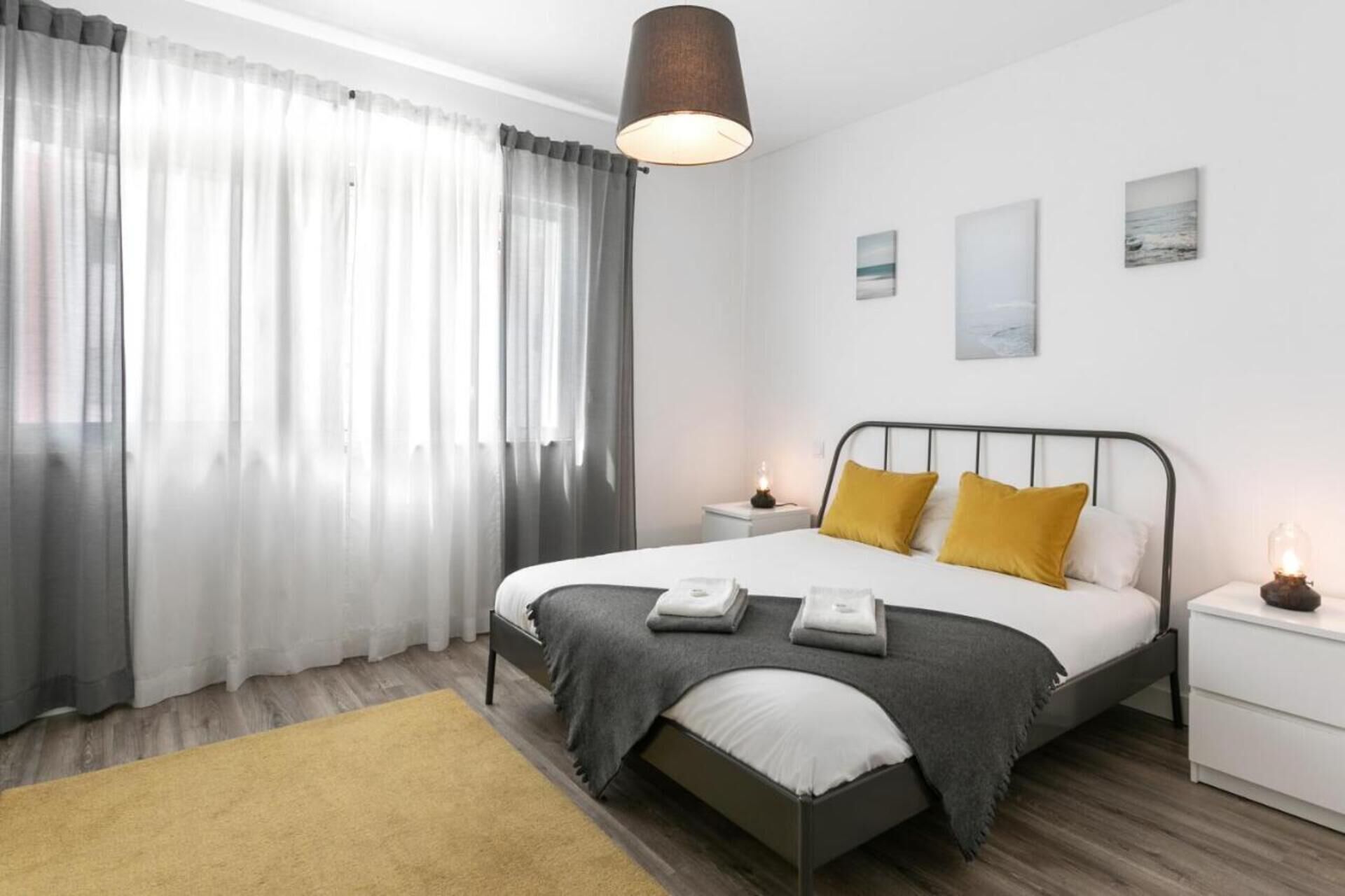 Een moderne slaapkamer met een bed, nachtkastjes en een bedtafeltje.