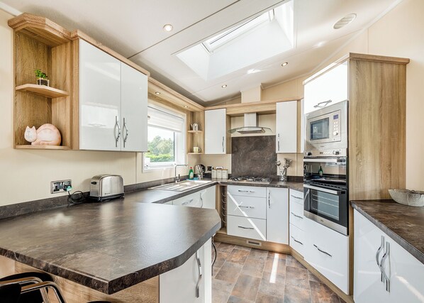 A modern kitchen with a central island, built-in appliances, and a window providing natural light.