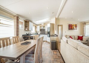 A modern kitchen with a dining area, a sofa, and a painting on the wall.