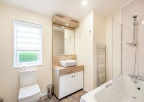Une salle de bain moderne équipée de toilettes, d’un lavabo, d’un miroir et d’une douche.