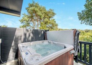 A hot tub on an outdoor deck with a view of trees and a clear sky. - Country and modern cladded lodge. (Kirkcudbright)