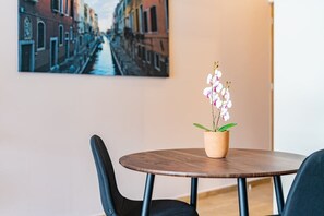 A round wooden table with a potted orchid in the center, flanked by two black chairs. - VH | Comfy loft | rooftop and wifi en Roma Nte | 304 (Ciudad de México)