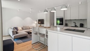 A modern kitchen with white cabinets, a central island, and pendant lighting. - 1 bedroom amazing apartment in Tossens (Tossens)