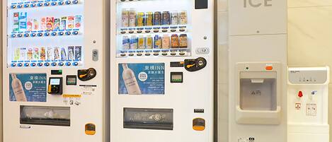 A row of vending machines with various beverages and a water dispenser.