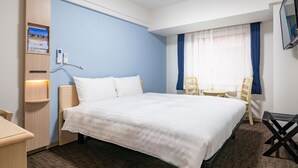 Une chambre d’hôtel avec un grand lit, un bureau, une chaise, une télévision et une fenêtre avec des rideaux.