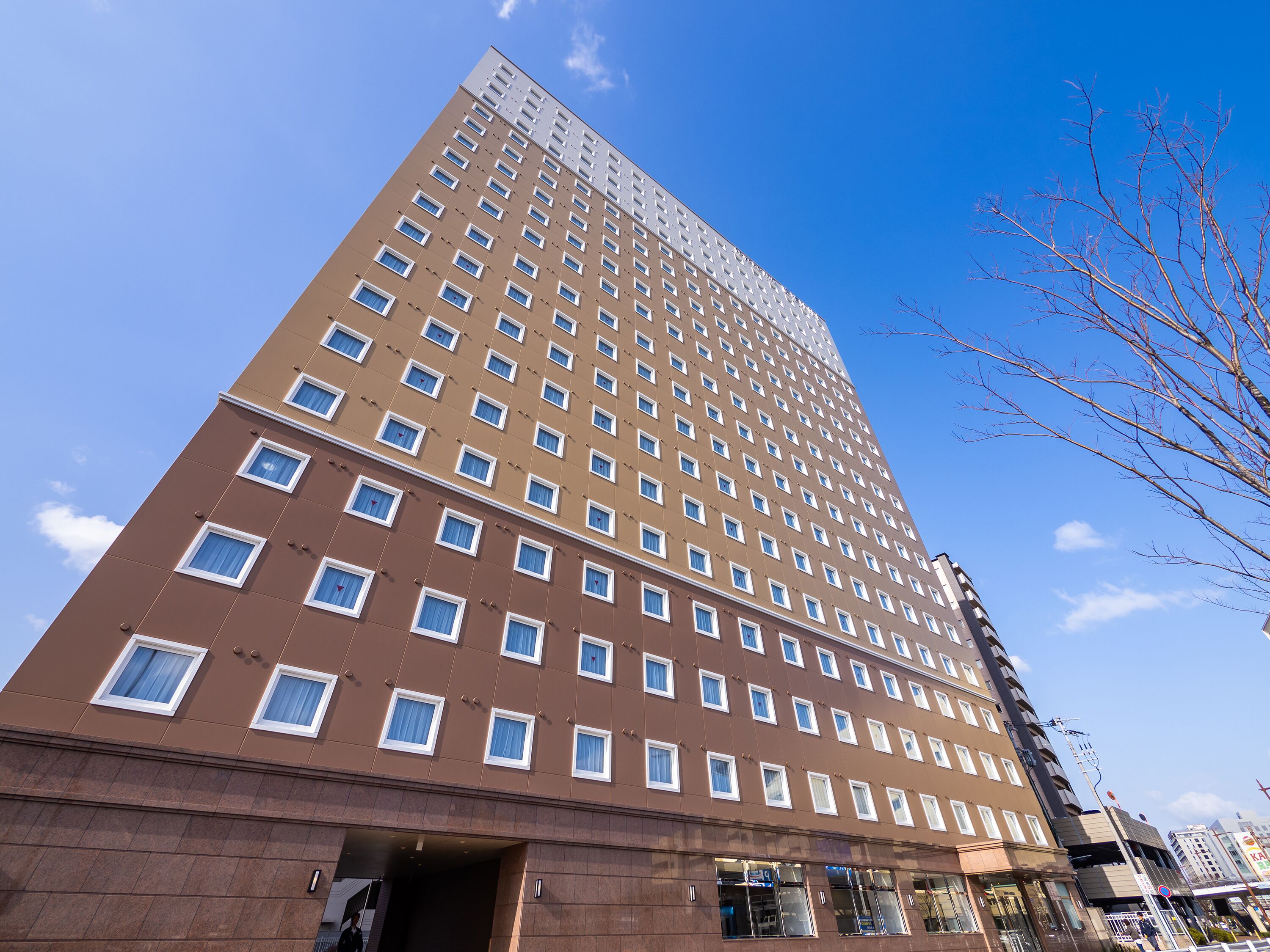 A tall hotel with multiple floors, a prominent entrance, and a clear view of the sky.
