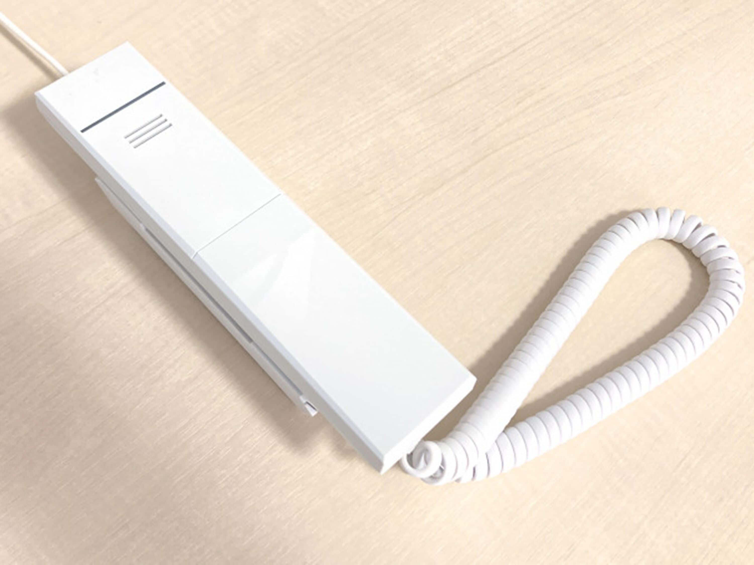 A white portable power strip with a coiled cable on a wooden surface.