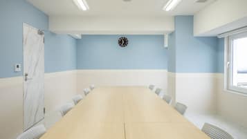 A conference room with a long table, chairs, a clock, and a window.