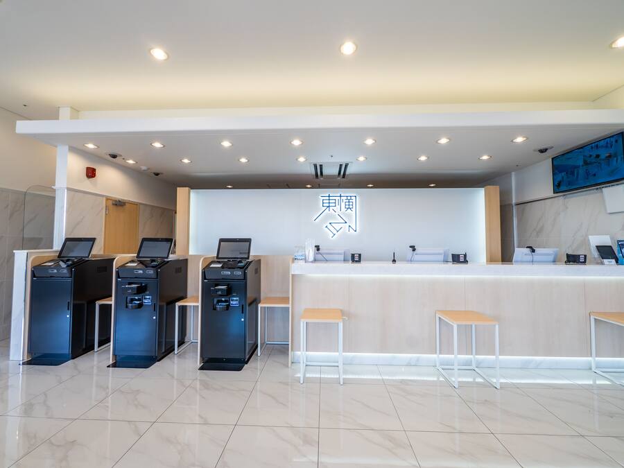 A modern reception area with a clean, minimalist design, featuring a reception desk, several computer stations, and a large illuminated sign.