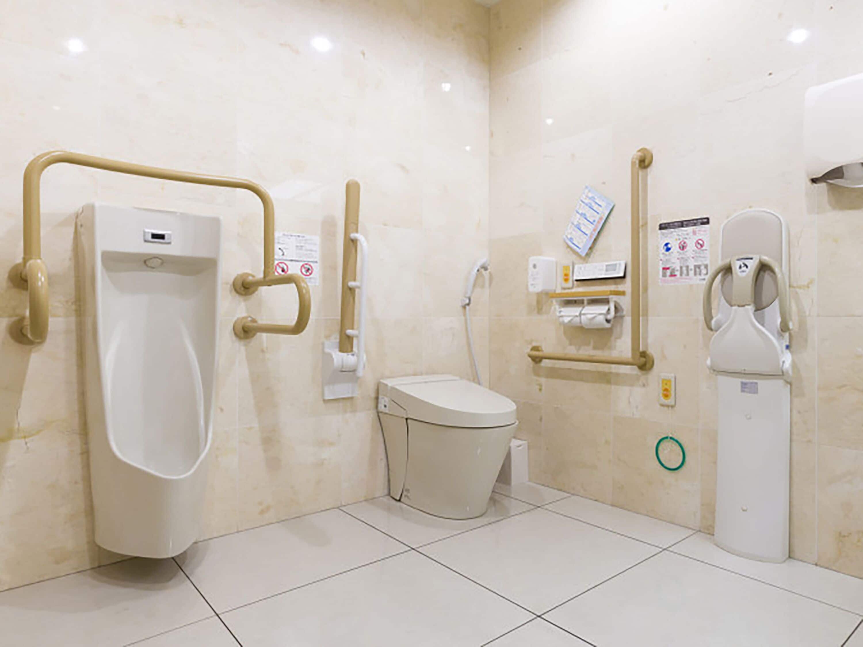 Des toilettes pour hommes comprenant un urinoir, des toilettes et un distributeur de gel hydroalcoolique.
