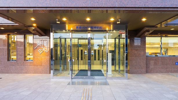 Une entrée moderne, avec une porte en verre et une rampe menant à l’intérieur du bâtiment.