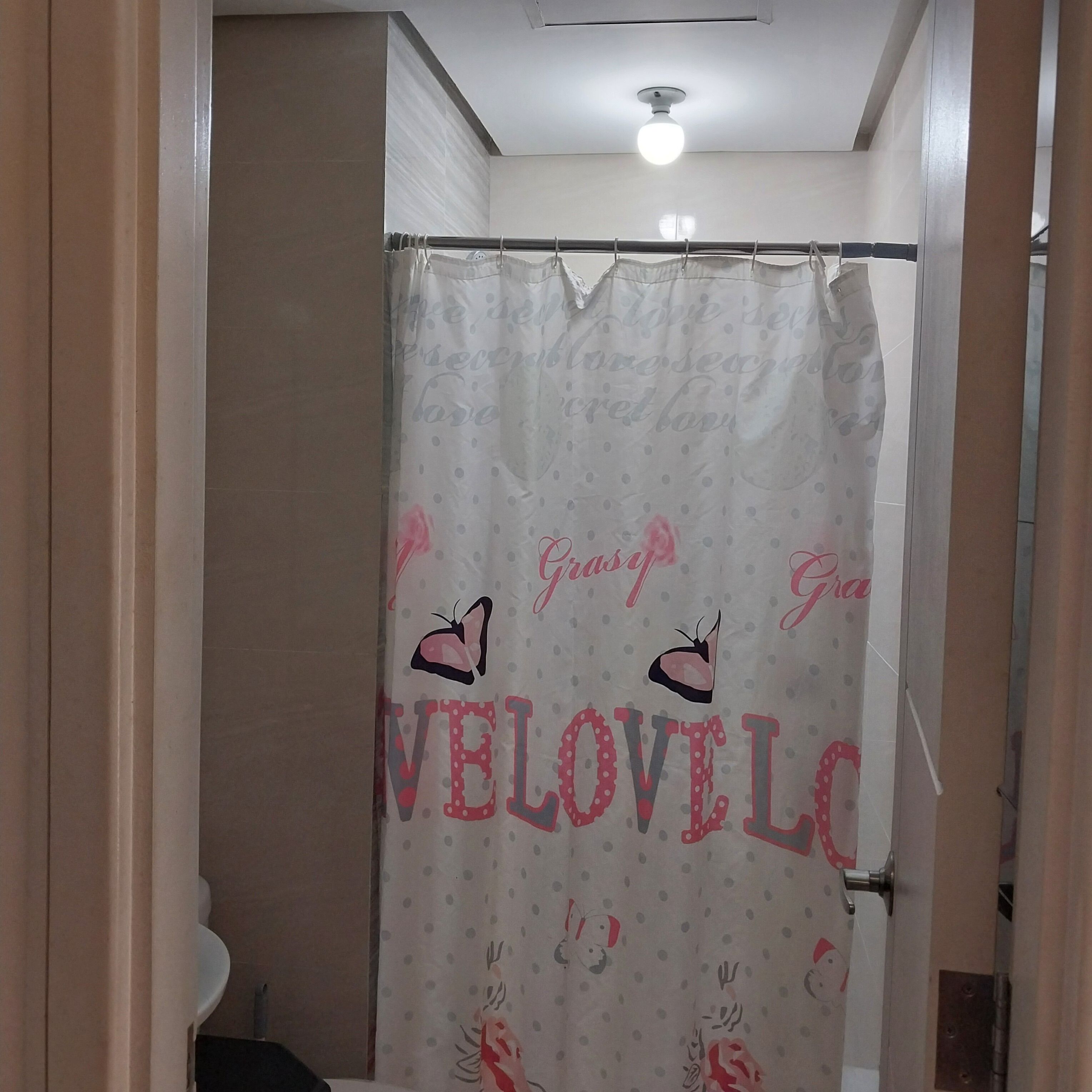 A bathroom with a shower curtain featuring a pattern of butterflies and the word "VELOVILE".