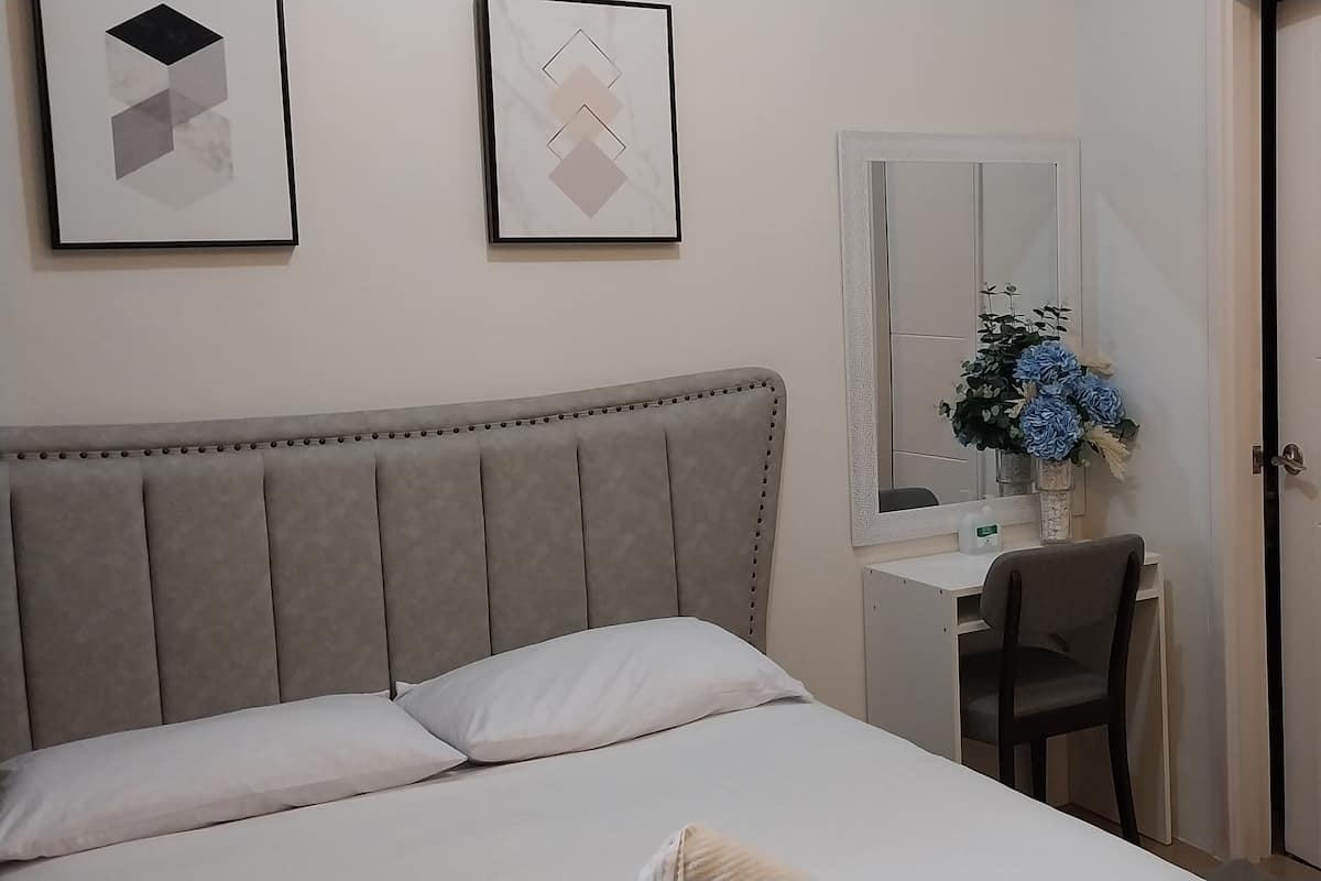 A bedroom with a bed, a desk, and a chair.