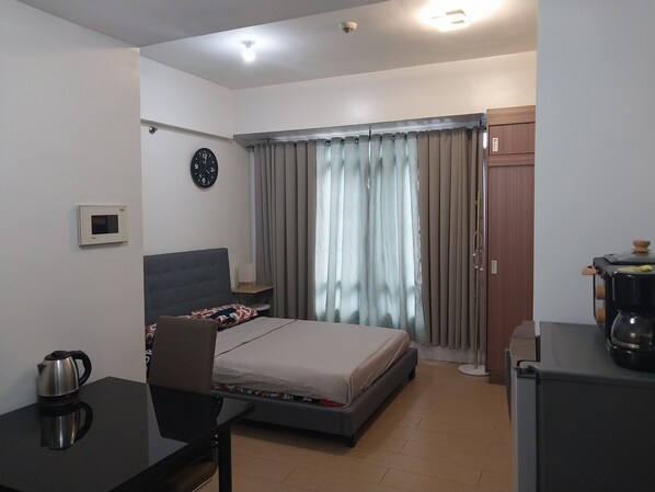 Une chambre d’hôtel moderne équipée d’un lit, d’un bureau, d’une machine à café et d’une horloge murale.