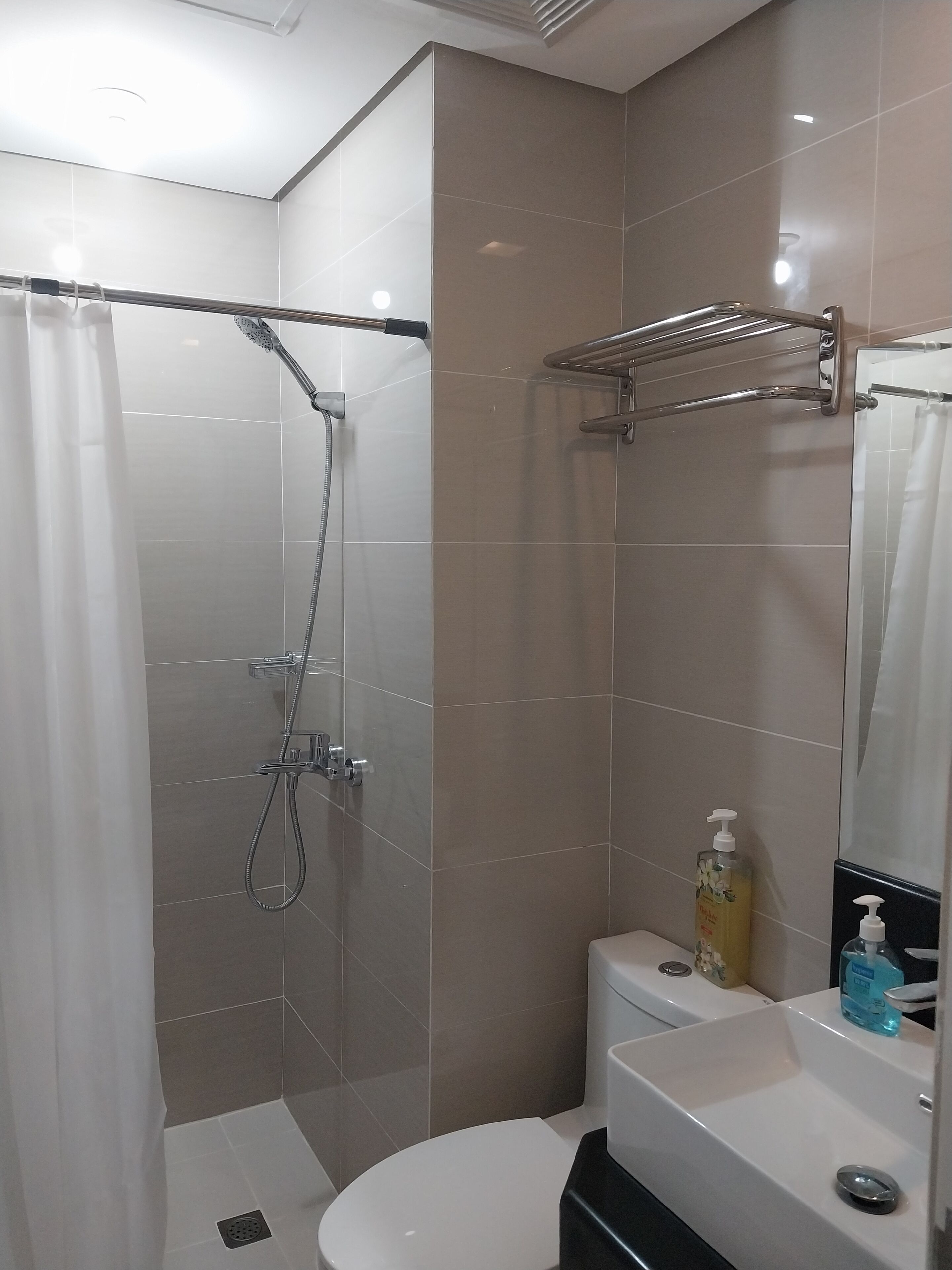 A modern bathroom with a shower, toilet, and sink.