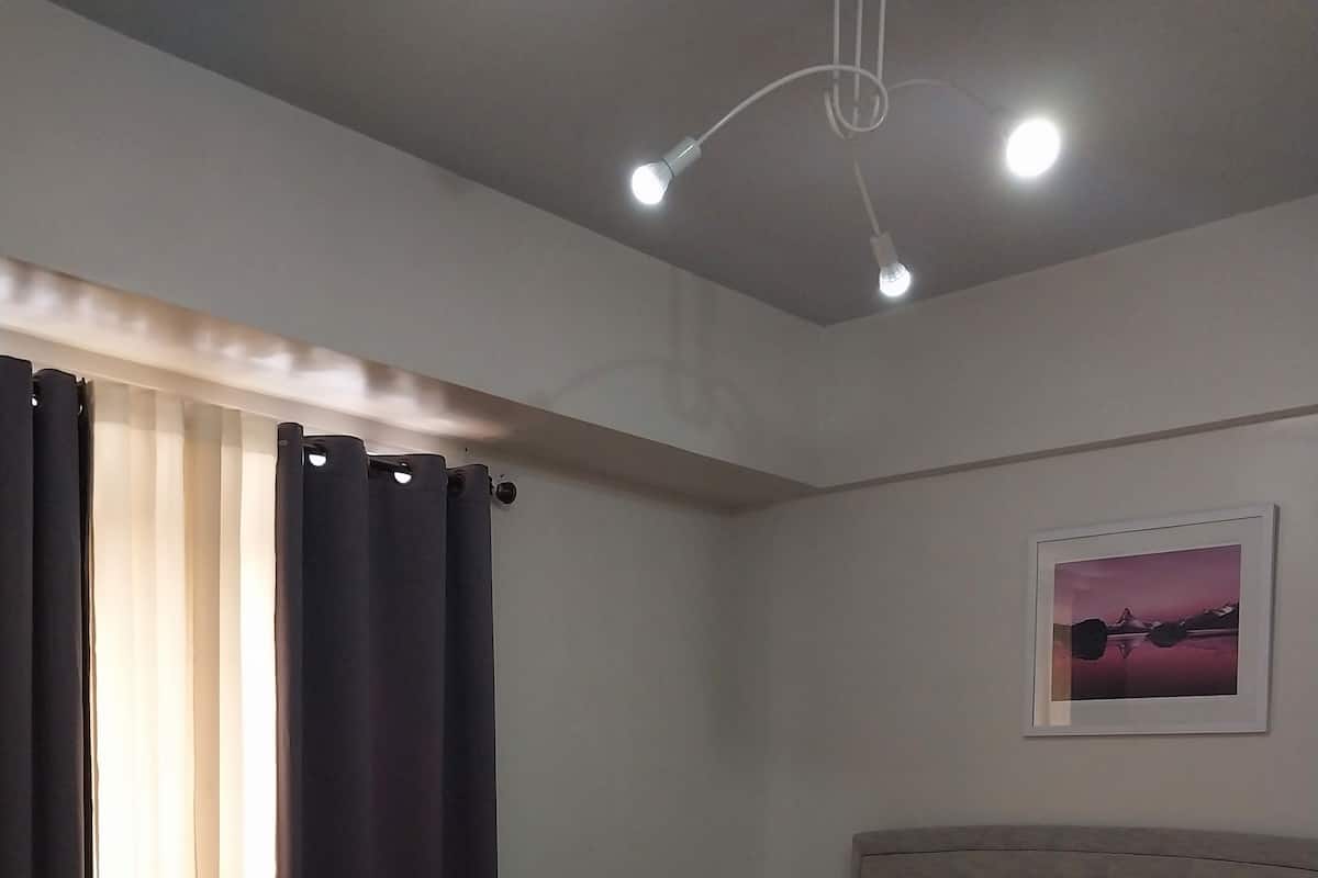 A bedroom with a bed, curtains, a nightstand, and a wall-mounted picture.