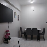 A conference room with a white table, four chairs, a flat-screen TV, and two framed pictures on the wall.