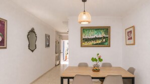 Un comedor con una mesa de madera, cuatro sillas, una lámpara colgante y un cuadro en la pared.