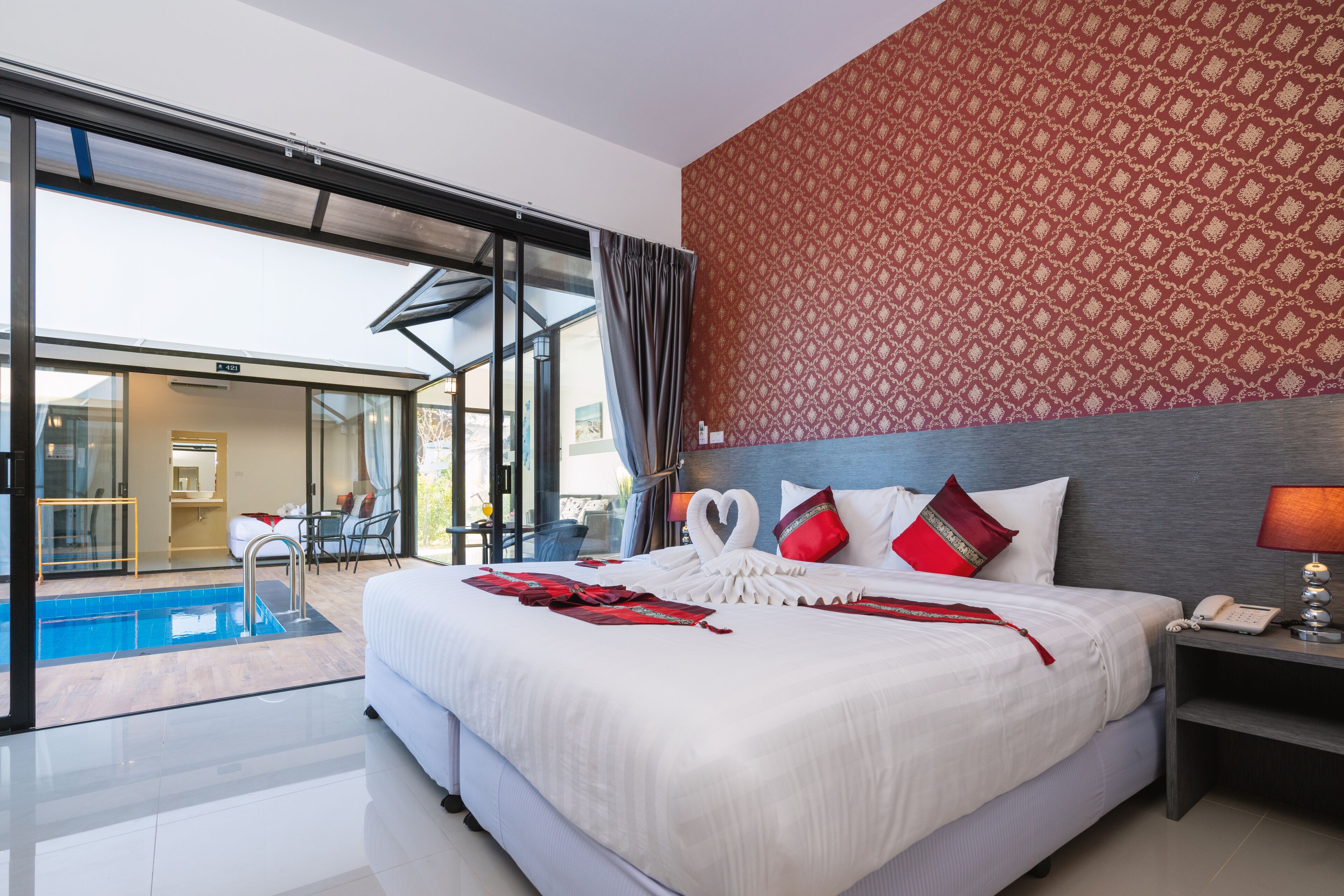A modern hotel room with a large bed, a pool, and a view of the outside.