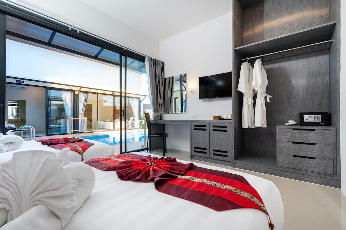 A modern hotel room with a large bed, a desk, a TV, and a view of a pool.