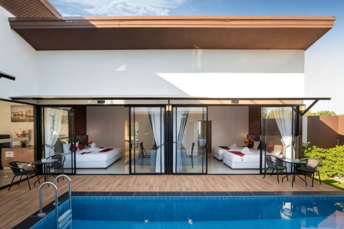 A modern building with a pool, glass sliding doors, and outdoor seating.