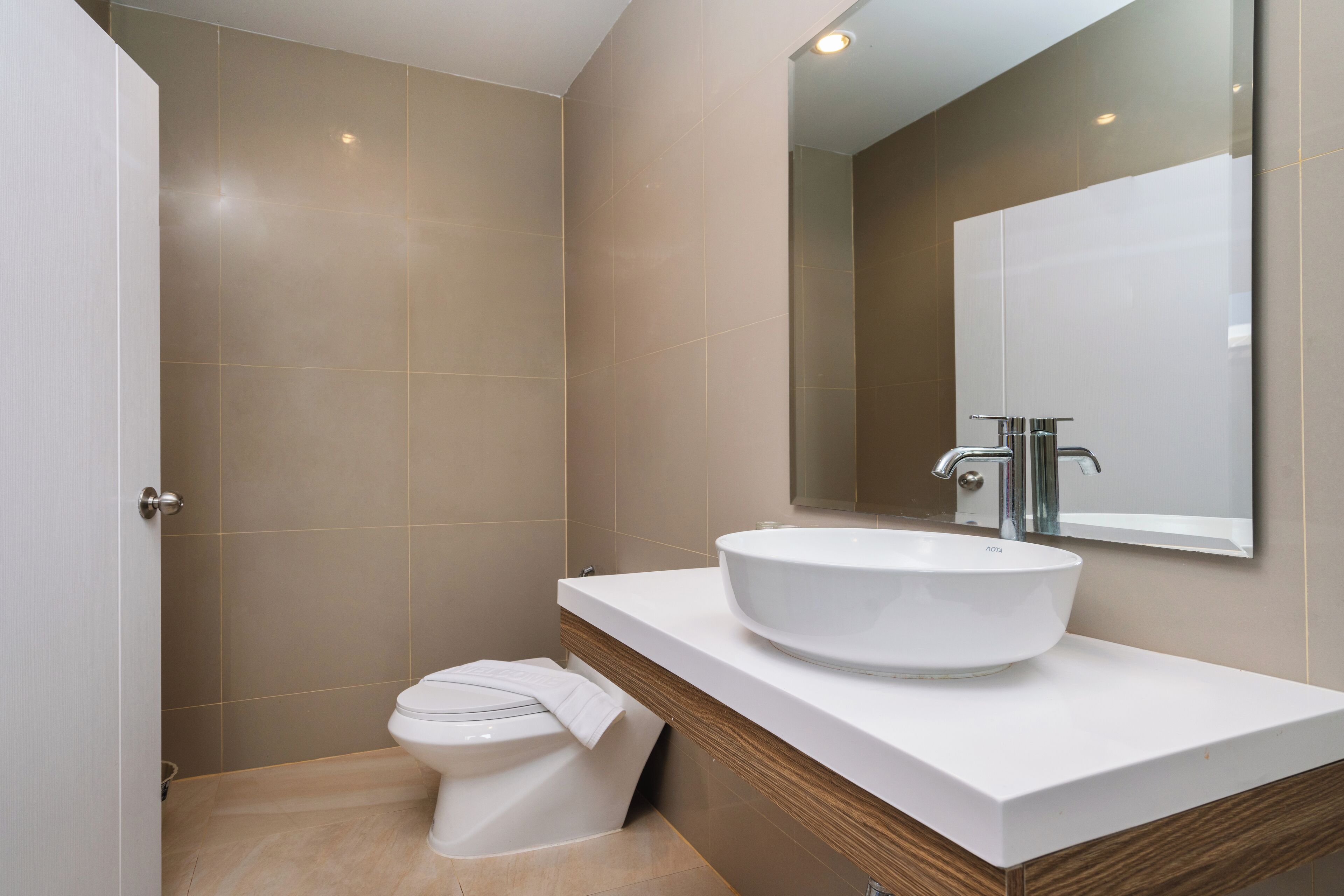 A modern bathroom with a white sink, a mirror, and a toilet.