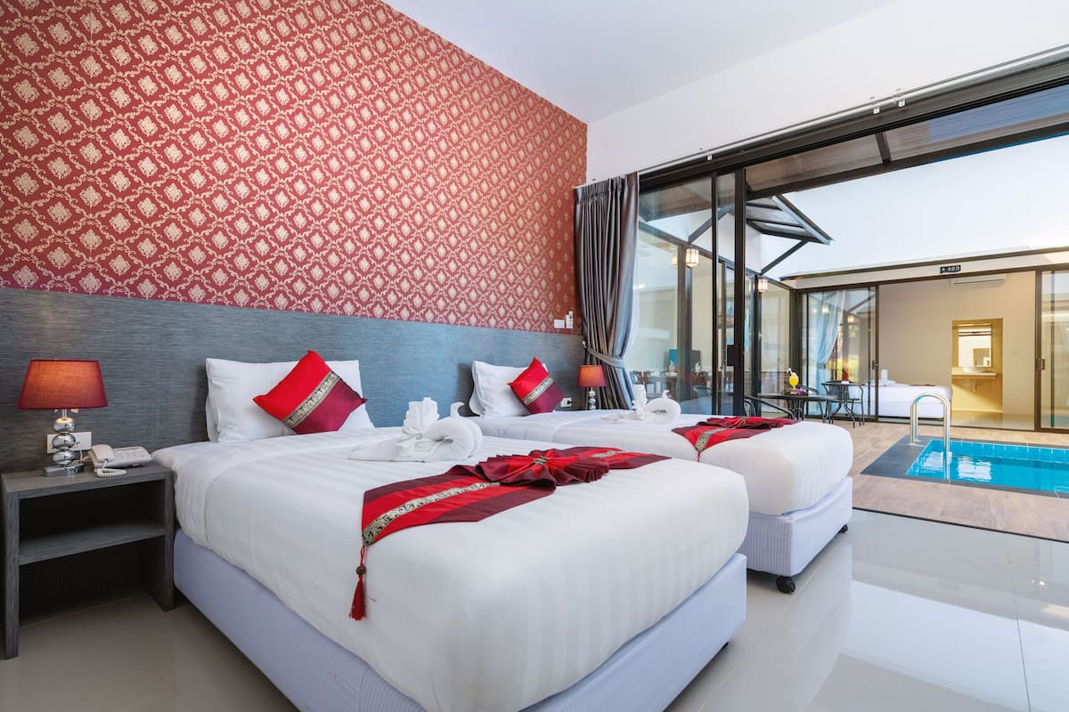 A hotel room with two beds, a pool, and a view of the pool area.