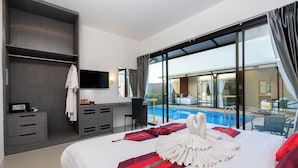 A hotel room with a large bed, a desk, a chair, a TV, and a view of a swimming pool. - Thames Tara Private Pool Villa Rawai Phuket (Rawai)