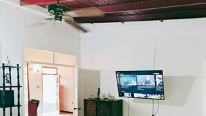 Un salón amplio con techo alto, un televisor montado en la pared y un aparador de madera.