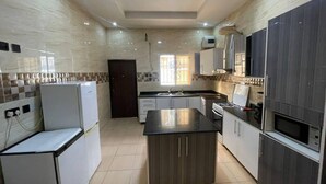 Une cuisine moderne avec des appareils électroménagers blancs, un îlot central et des meubles de rangement de couleur foncée.