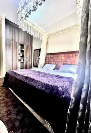 Une chambre avec un grand lit, une armoire et un miroir.