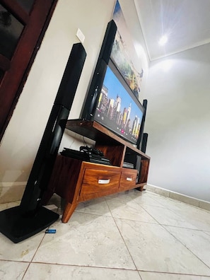 A flat-screen TV on a wooden entertainment unit with a cityscape on the screen.