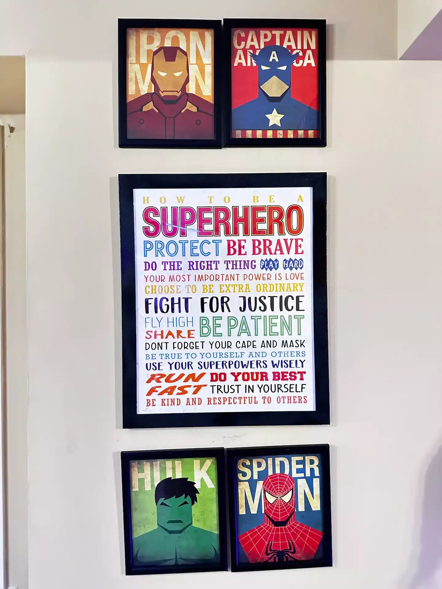 Eine Wand mit gerahmten Superhelder-Postern, darunter Iron Man, Captain America, Hulk und Spider-Man.
