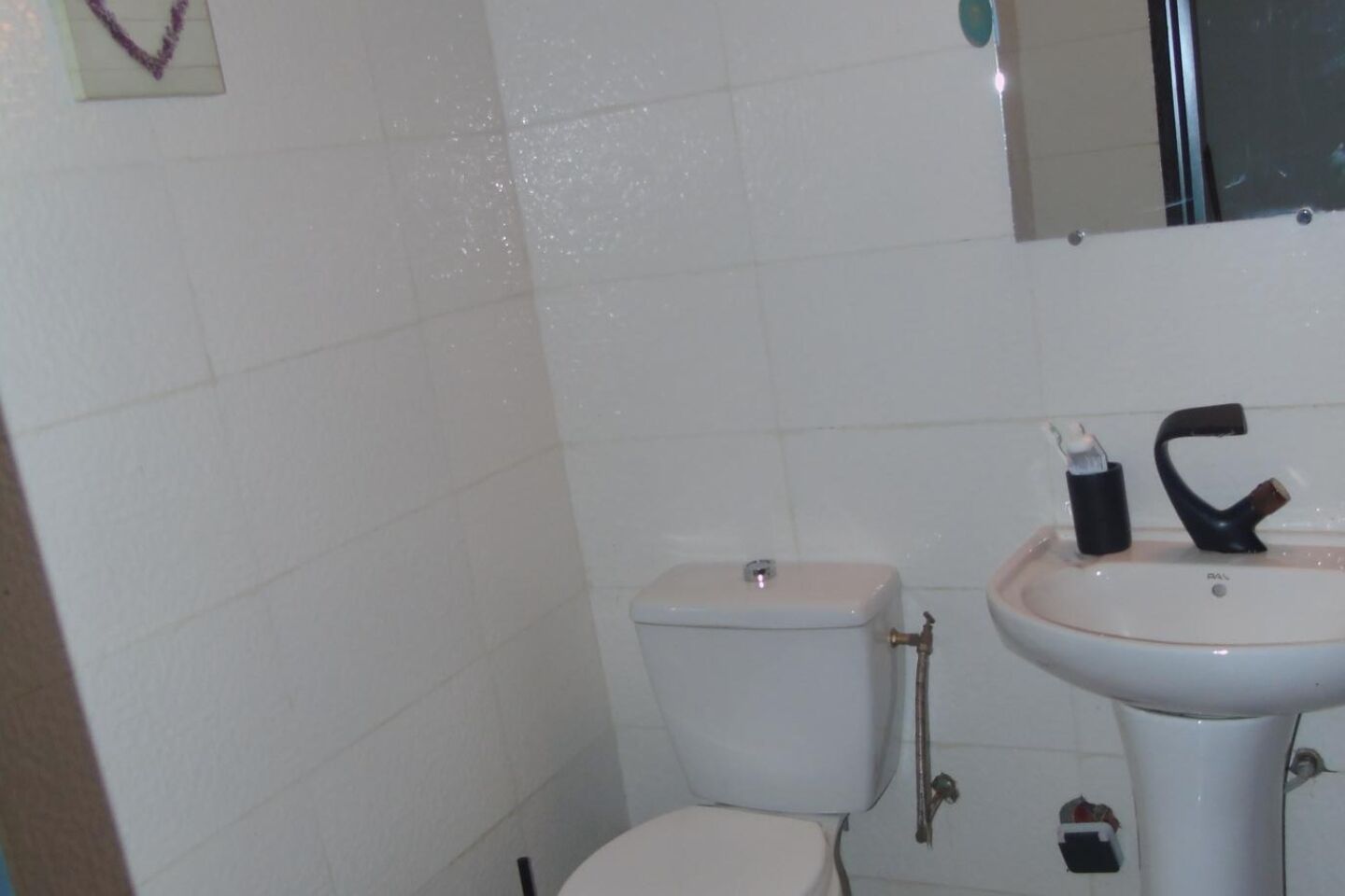 Ein kleines Badezimmer mit Toilette, Waschbecken und Spiegel.