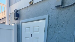 Una puerta blanca con el número 'B', un buzón y una lámpara fijada a la pared.