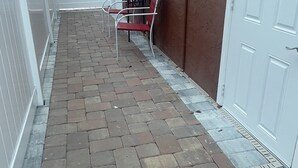 Un patio empedrado con una puerta blanca y una silla roja.