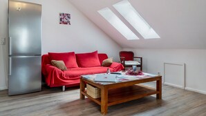A modern living room with a red sofa, a wooden coffee table, a silver refrigerator, and a skylight. - Ferienwohnung Rebberg 2 – klimatisierte Unterkunft mit WLAN, Bergblick und Wallbox (Wolfach)