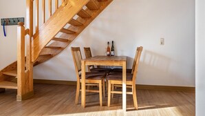 Una escalera de madera que conduce a un comedor con una mesa y sillas.