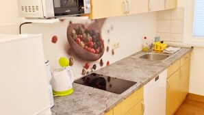 Una cocina con microondas, estufa, lavabo y un frutero en la pared.