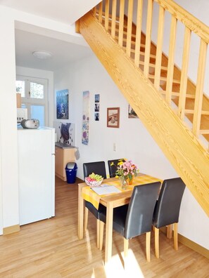 A dining area with a wooden table, black chairs, and a vase with flowers. - Holiday Apartment 'Schwalbennest' with Terrace & Wi-Fi (Buchholz Müritz)