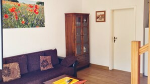 Una sala de estar con un sofá, un mueble de madera, una mesa de centro y un cuadro en la pared.