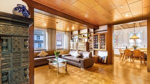 A spacious living area with a wooden ceiling, a brown leather sofa, a glass coffee table, and a fireplace with intricate metal detailing. - Apartment 'Michelskäppele' with Mountain View, Shared Terrace and Wi-Fi (Bad Urach)