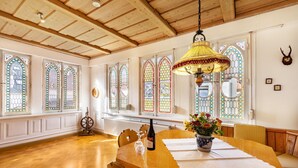 A dining area with a wooden table, chairs, a chandelier, and stained glass windows. - Apartment 'Michelskäppele' with Mountain View, Shared Terrace and Wi-Fi (Bad Urach)