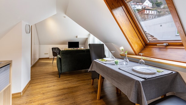 A dining area with a table set for two, a black chair, and a view through a skylight. - Premium Apartment 'Hohenurach' with Mountain View, Shared Terrace and Wi-Fi (Bad Urach)