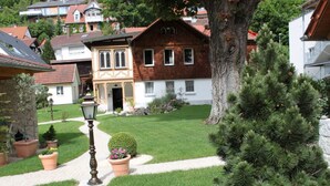 A well-maintained garden with a pathway, a lamp post, and a large pine tree. - Apartment 'Güterstein' with Mountain View, Shared Terrace and Wi-Fi (Bad Urach)