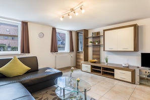 Una sala de estar moderna con un sofá, una mesa de centro de vidrio, un mueble de madera y un espejo grande.