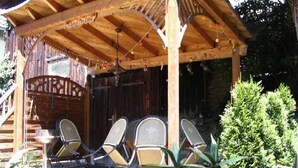 A wooden gazebo with a covered seating area, a staircase, and a small table with potted plants. - Apartment 'Güterstein' with Mountain View, Shared Terrace and Wi-Fi (Bad Urach)