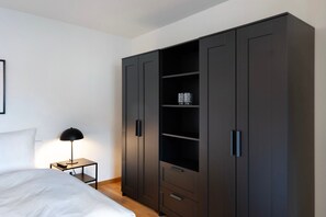 Une chambre à coucher avec un lit, une table de chevet avec une lampe et une grande armoire.